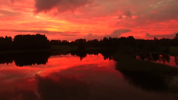 Aerial view of a lake with reflection of the pink sky in Estonia.