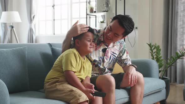 Sad Child Sitting With His Father On A Couch While He Is Watching Tv