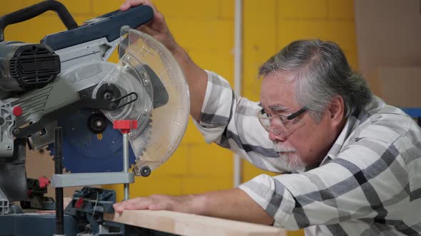 Senior man use electric cutter to cut wood