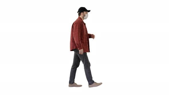 American Farmer in a Cap and Medical Mask Walks Along on White Background.