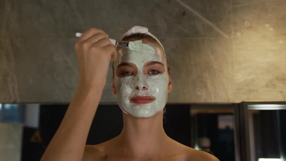 Caucasian woman putting on face mask in hotel