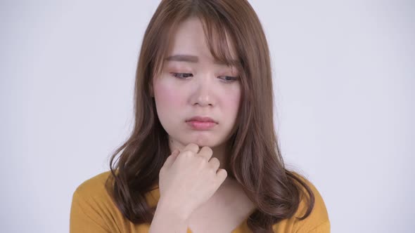 Face of Young Serious Asian Woman Thinking While Looking Down