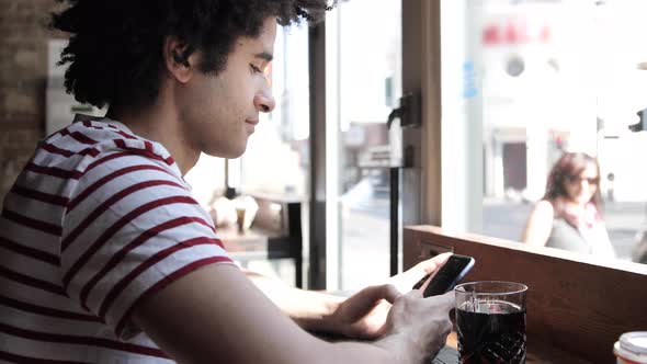 Man at cafe typing on mobile phone