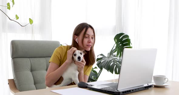 Young Woman Works on a Laptop While Sitting with Her Adorable Dog