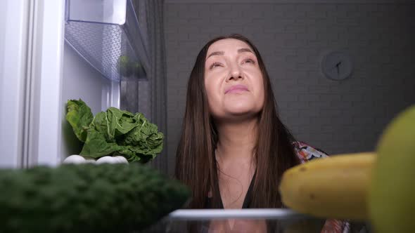 Thoughtful Woman Looks for Snacks and Chooses Green Apple