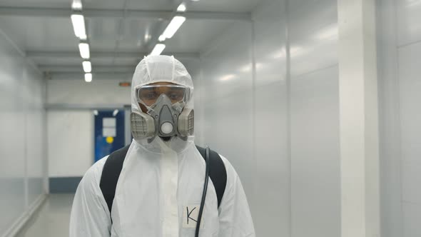 Portrait of Doctor on Hazmat Overall and Respiratory Mask Looking at Camera in Hospital Hallway