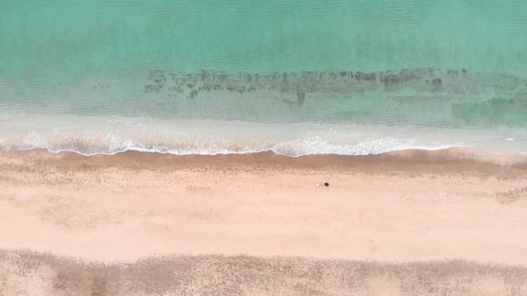 Clear turquoise sea water and golden sand beach, aerial top view