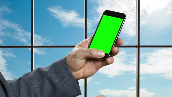 Man with Smartphone on the Background of a Large Window.