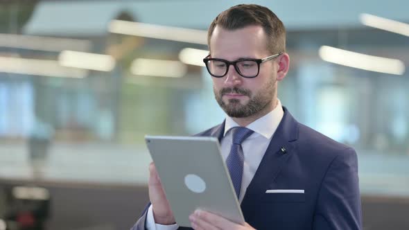 Portrait of Middle Aged Businessman Using Digital Tablet