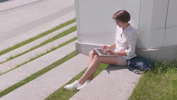 Business Woman in Eyeglasses Works with Laptop in Urban Park