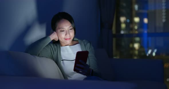 Asian woman look at cellphone and sit on couch