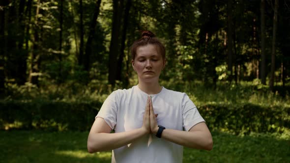 A Woman Meditates Among the Trees Opens Her Eyes Looks at the Camera