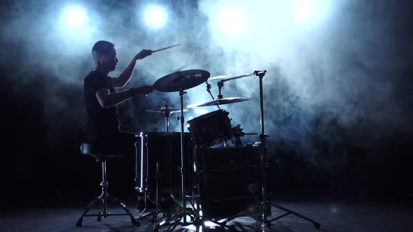 Musician Plays Professionally Good Music on Drums Using Sticks. Smoky Background. Silhouette. Slow