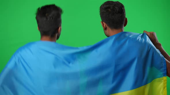 Back View Two Middle Eastern Men Wrapped in Ukrainian Flag Rejoicing Goal Watching Football Match at