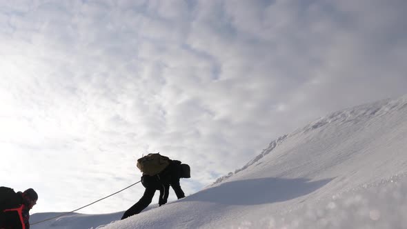 Three Alpenists in Winter Climb Rope on Mountain. Travelers Climb Rope To Their Victory Through Snow