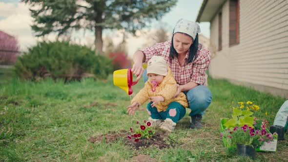 The Daughter Helps Her Mother to Water the Flowers in the Garden