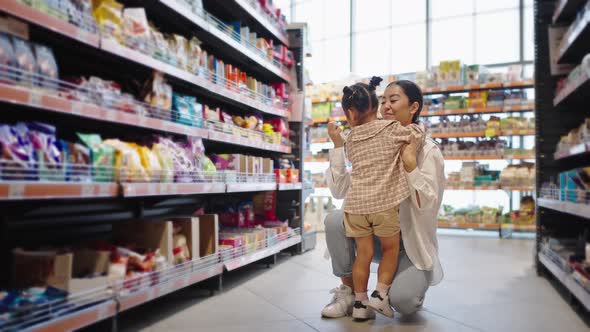 Happy Mother Gives Present Hugging Daughter in Supermarket