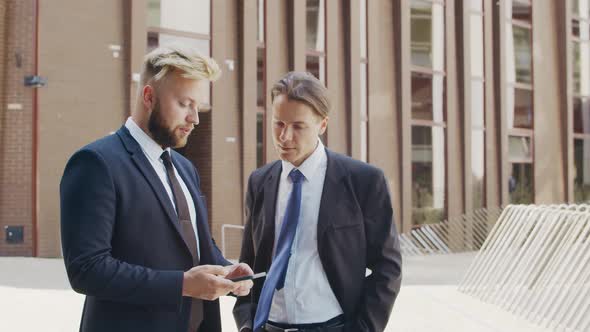 Confident businessman and his colleague in front of modern office building.