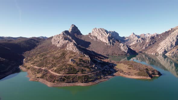 Sharp, tall mountain range bext to a greenish water lake in León, Spain. Rocky mountains reflected o