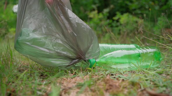 Worker cleaner remove garbage rubbish in bag at forest meadow. Sunny day. Slow motion. Closeup