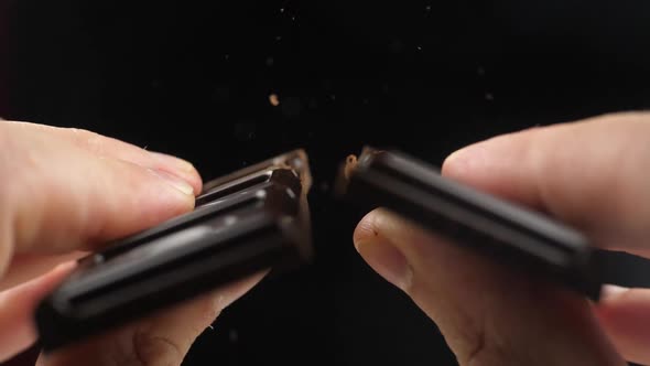 Hands break a bar of chocolate. Slow-motion