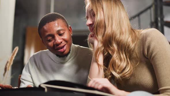 Happy Man with Pretty Woman Looks at Pictures of Family