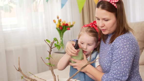 a Mother and Daughter Spray the Houseplant with Water