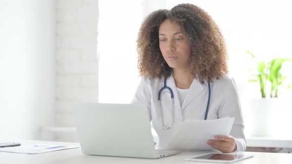 Afrcian Doctor Reading Documents while Sitting in Clinic