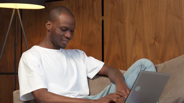 Young Happy Black Man Communicates Online on a Laptop