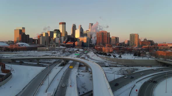 Minneapolis downtown skyline aerial footage during a winter golden hour, highways covered with snow,