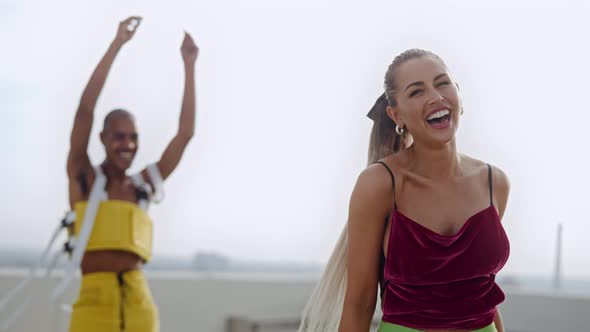 Two Fashion Models Dancing And Laughing In Clubwear On City Roof