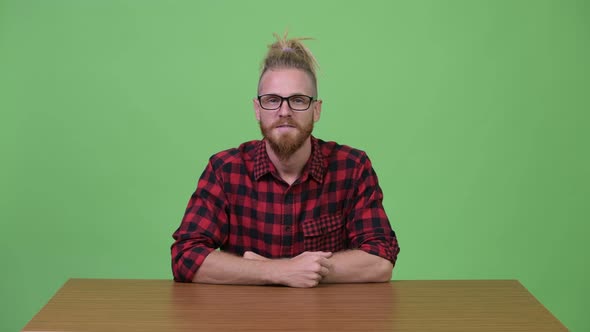 Happy Bearded Hipster Man Smiling Against Wooden Table