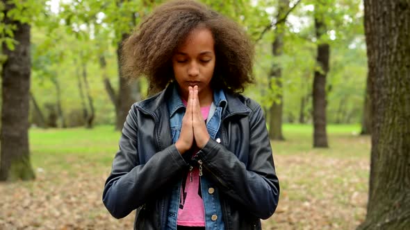 Young Sensitive Girl Closed Eyes and Start To Pray in the Park