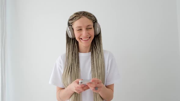 Smiling Woman Listening to Music on Smartphone in Wireless Headphones