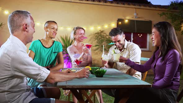 Five Adult Friends Toasting Cocktails and Having Fun in a Outdoor Bar
