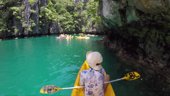 Girl kayaking on yellow boat in Big lagoon in Philippines