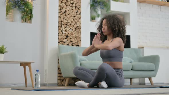 Peaceful Young African Woman Meditating on Yoga Mat at Home