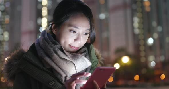 Woman use of mobile phone in city at night