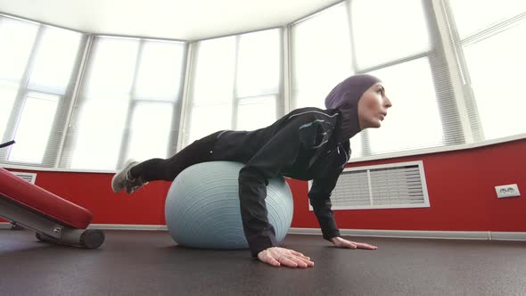 Girl in Hijab on Fitness Ball in Gym