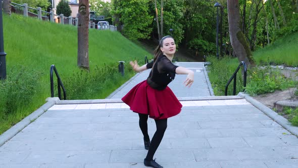 Female dancer dances outside in the park at day time