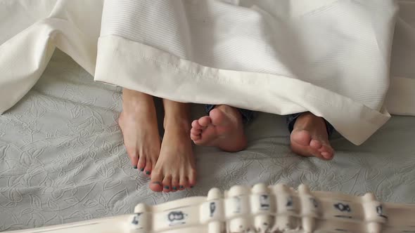 Closeup of Feet in a Bed Under White Blanket