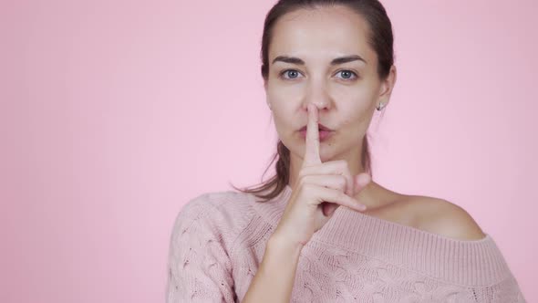 Woman Holding Finger on Lips, Gesture of Silence, Isolated on Pink Background