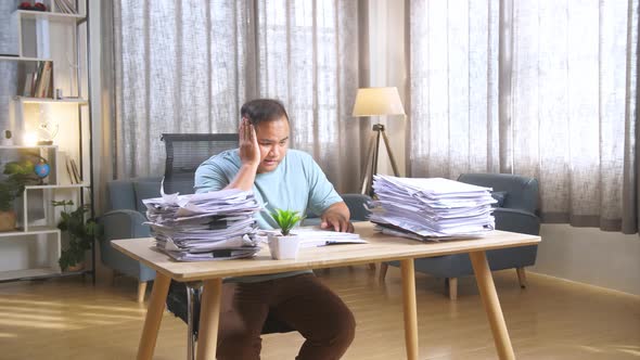 Tired Fat Asian Man Sitting On The Office Chair And Putting Hand On Cheek While Working Hard With Do