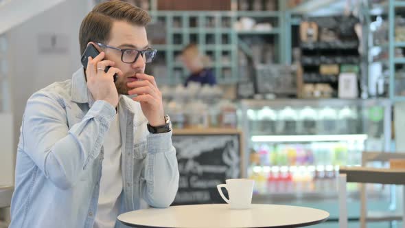 Man Talking on Phone in Cafe