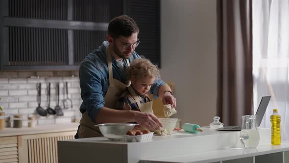 Adult Man and His Little Son are Preparing Surprise for Mother Cooking Breakfast Together at Kitchen