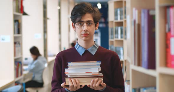 Male College Student Holding Books Smiling Happily Standing in Library