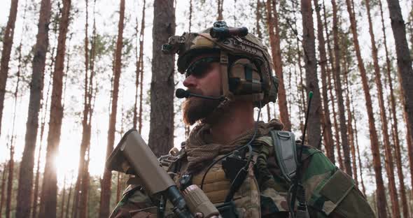 Portrait of a Bearded Middleaged Soldier in a Woodland Military Uniform and a Helmet with Headphones