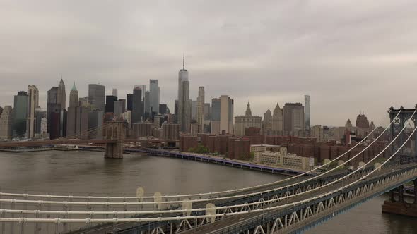 An aerial view over the East River on a cloudy day. The drone camera hovers above the Manhattan Brid