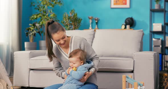 A Strong Woman is Resting on Mat on the Living Room Floor with a Child