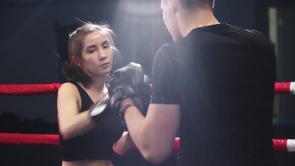 Young Woman with Long Hair Training Boxing with Her Personal Trainer on the Ring